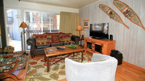 A living room with a sofa, a television, a wooden cabinet, and a patterned rug. - Sierra Park Villas #16 (Mammoth Lakes)