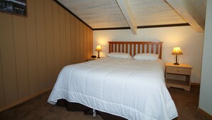 A bedroom with a large bed, two bedside tables with lamps, wooden headboard, and a framed picture on the wall. - Sierra Park Villas #29 (Mammoth Lakes)