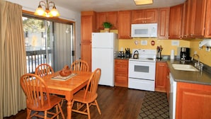 A compact kitchen with wooden cabinets, a white refrigerator, a microwave, and a stove. - Sierra Park Villas #29 (Mammoth Lakes)