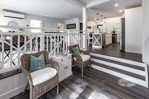 Staircase leads to an upper level with a picture above, complemented by a cozy seating area and modern kitchen.