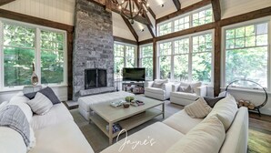 A spacious living room with a stone fireplace, large windows, and a chandelier. - 5-year old, Luxury Build on Joe! Immaculate Main + Guest Cottage! Tennis! (Mactier)