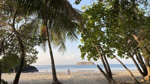 Une plage bordée de palmiers et sur laquelle on peut voir un panneau indicateur.