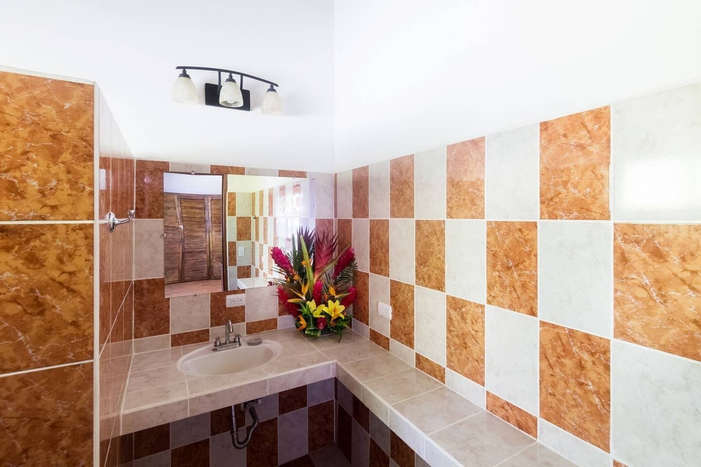 Een badkamer met een wastafel, spiegel en douche.