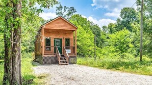 Une cabane en bois dotée d’un porche et d’un escalier menant à l’entrée.