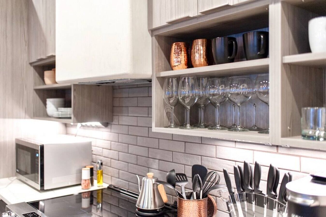 A modern kitchen with a microwave, a coffee maker, and a knife block on the counter.