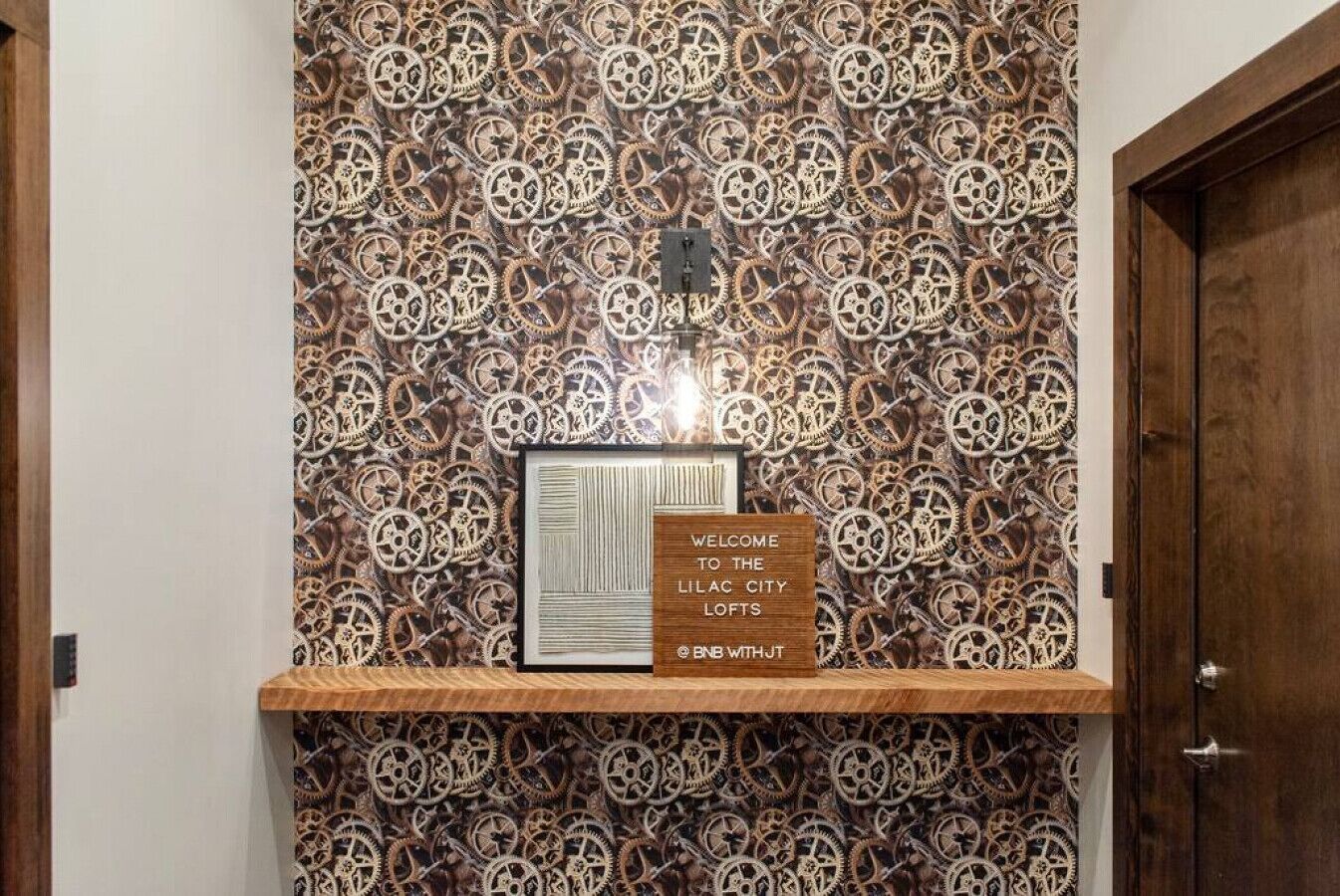 A wall with a gear pattern wallpaper and a welcome sign for Lilac City Lofts.