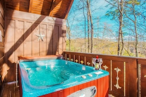 A hot tub with a wooden deck and a star decoration, surrounded by trees.