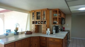 A kitchen with wooden cabinets, a built-in microwave, and a coffee maker. - WATER FRONT SWEET HOME (Mesa)