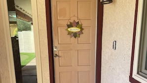 A beige door with a brown frame, a welcome sign, a doormat, and a wall-mounted light fixture. - WATER FRONT SWEET HOME (Mesa)