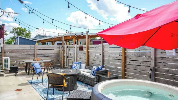An outdoor patio area with a hot tub, wicker furniture, and string lights. - Downtown Solar Home w/ Hot Tub & Billiards (Geneva)