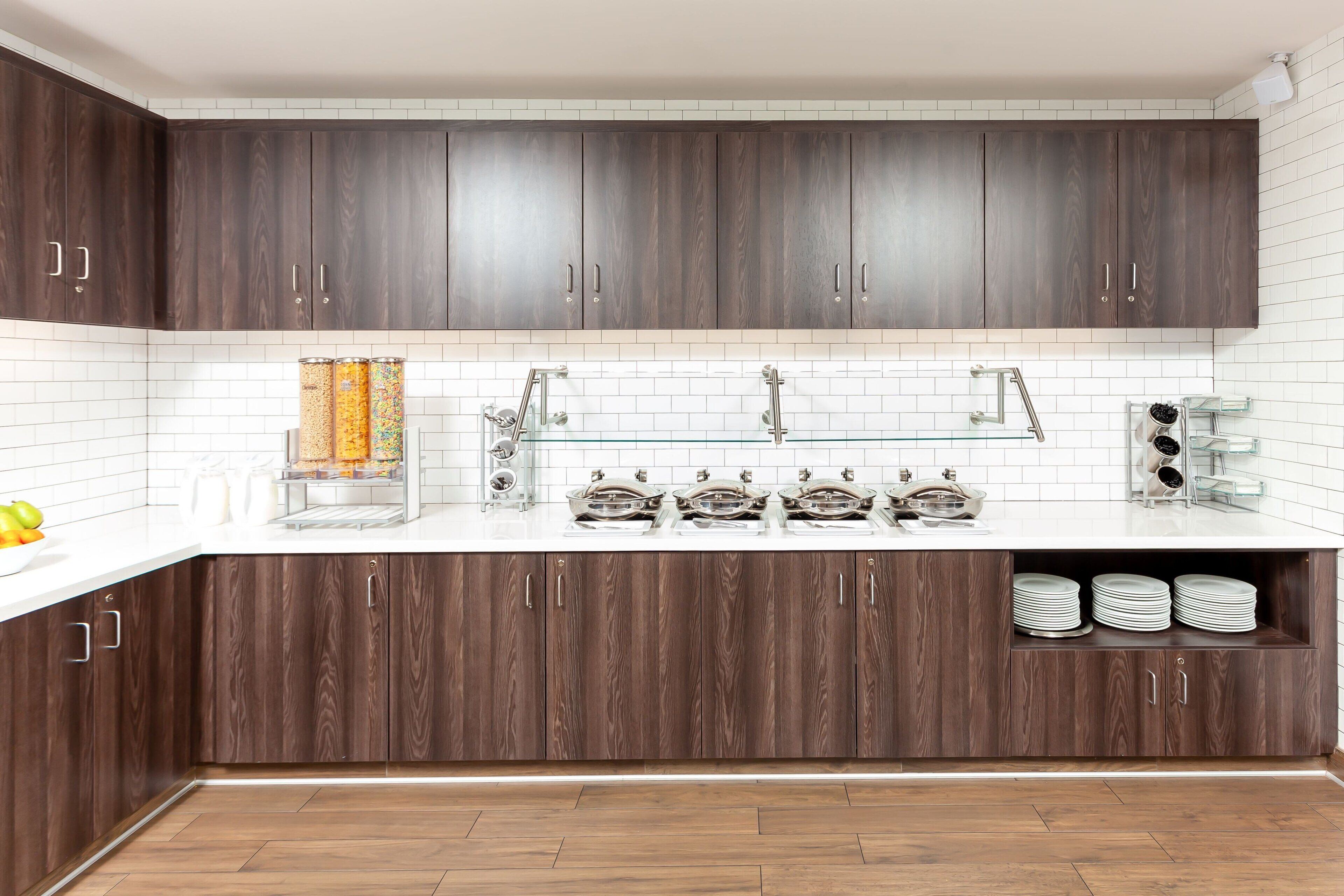 A modern kitchen with dark wood cabinets, white subway tiles, and a white countertop.
