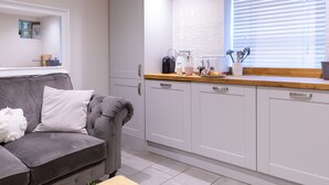 Eine moderne Küche mit weißen Schränken, einem grauen Sofa und einer Holzarbeitsplatte.