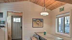 A cozy interior with a wooden ceiling, a bench, a table with a candle, and a window with a view of trees. - Views high above the river with a pleasant walk to Midtown shops and food. (Ruidoso)