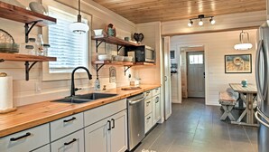 Une cuisine moderne avec des étagères en bois, un évier et un lave-vaisselle.