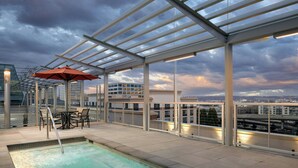 A rooftop pool with a glass enclosure, outdoor seating, and a city view. - Marriott Tacoma Downtown (Tacoma)