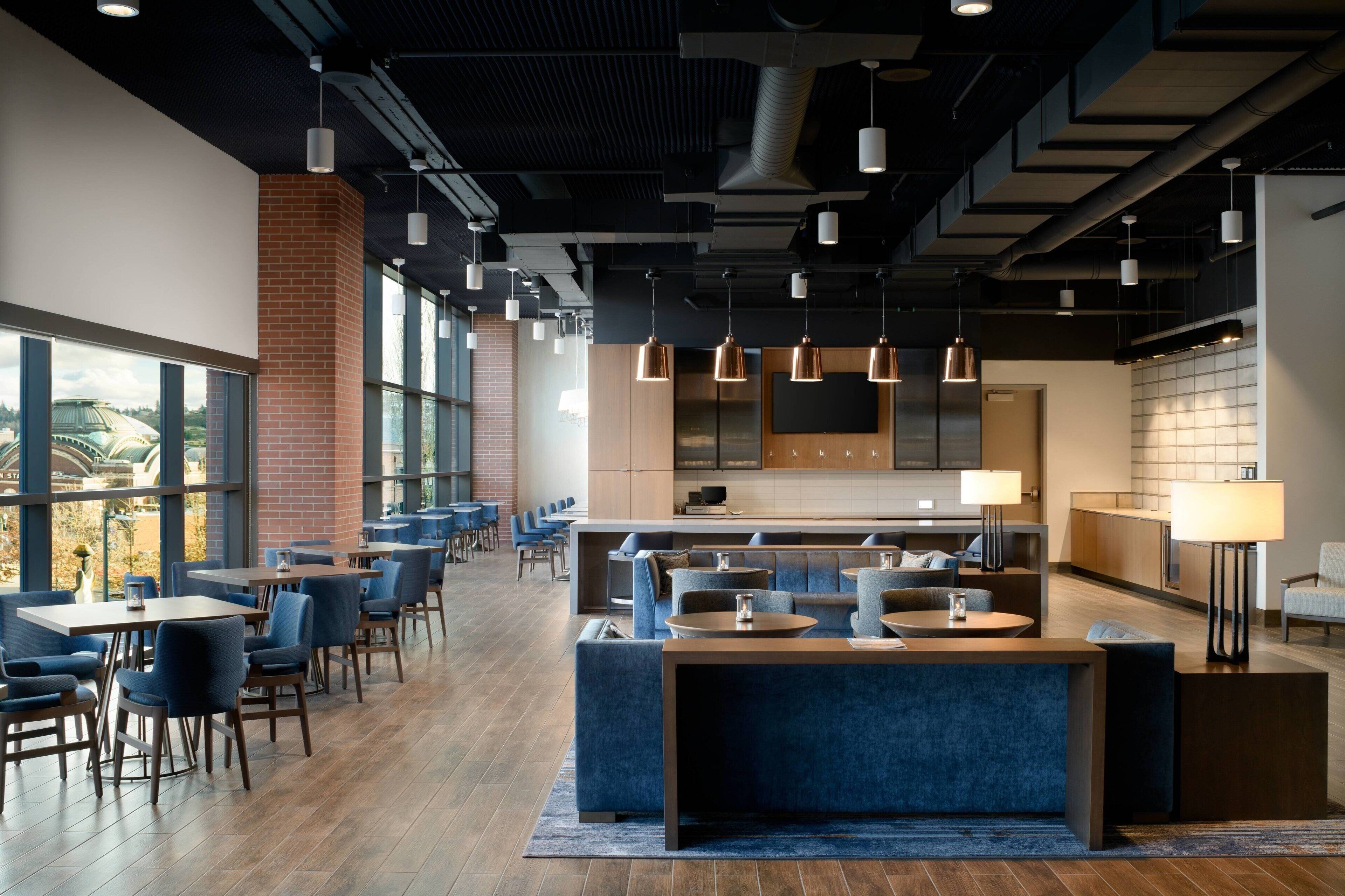 A modern lounge area with seating arrangements, a bar, and a kitchen area.