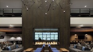 A modern lounge area with a bar, sofas, and a large window overlooking a cityscape. - Marriott Tacoma Downtown (Tacoma)
