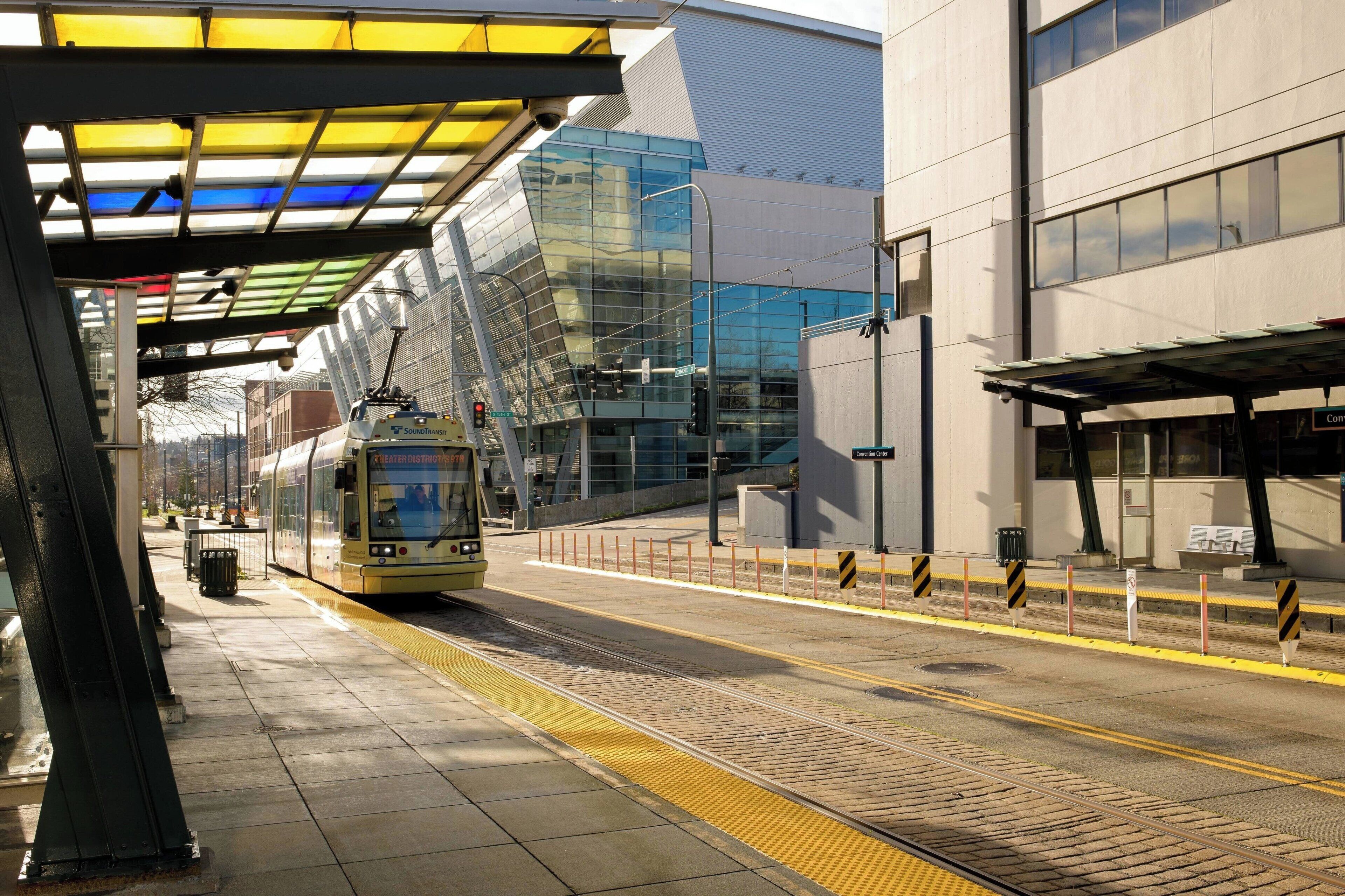 A modern train station with a covered platform, a glass building, and a clear sky.