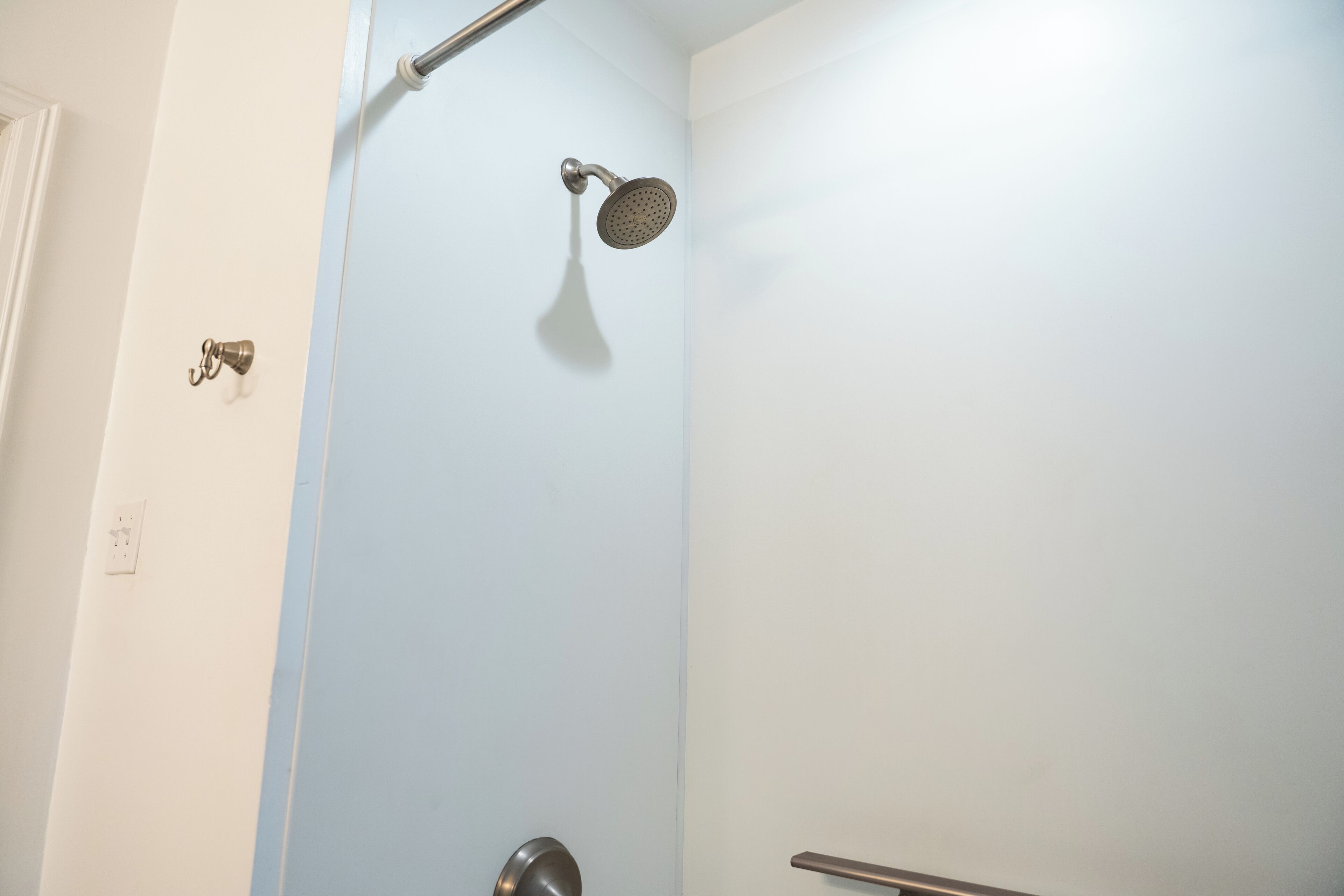 A bathroom with a shower, a door, and a towel rack.