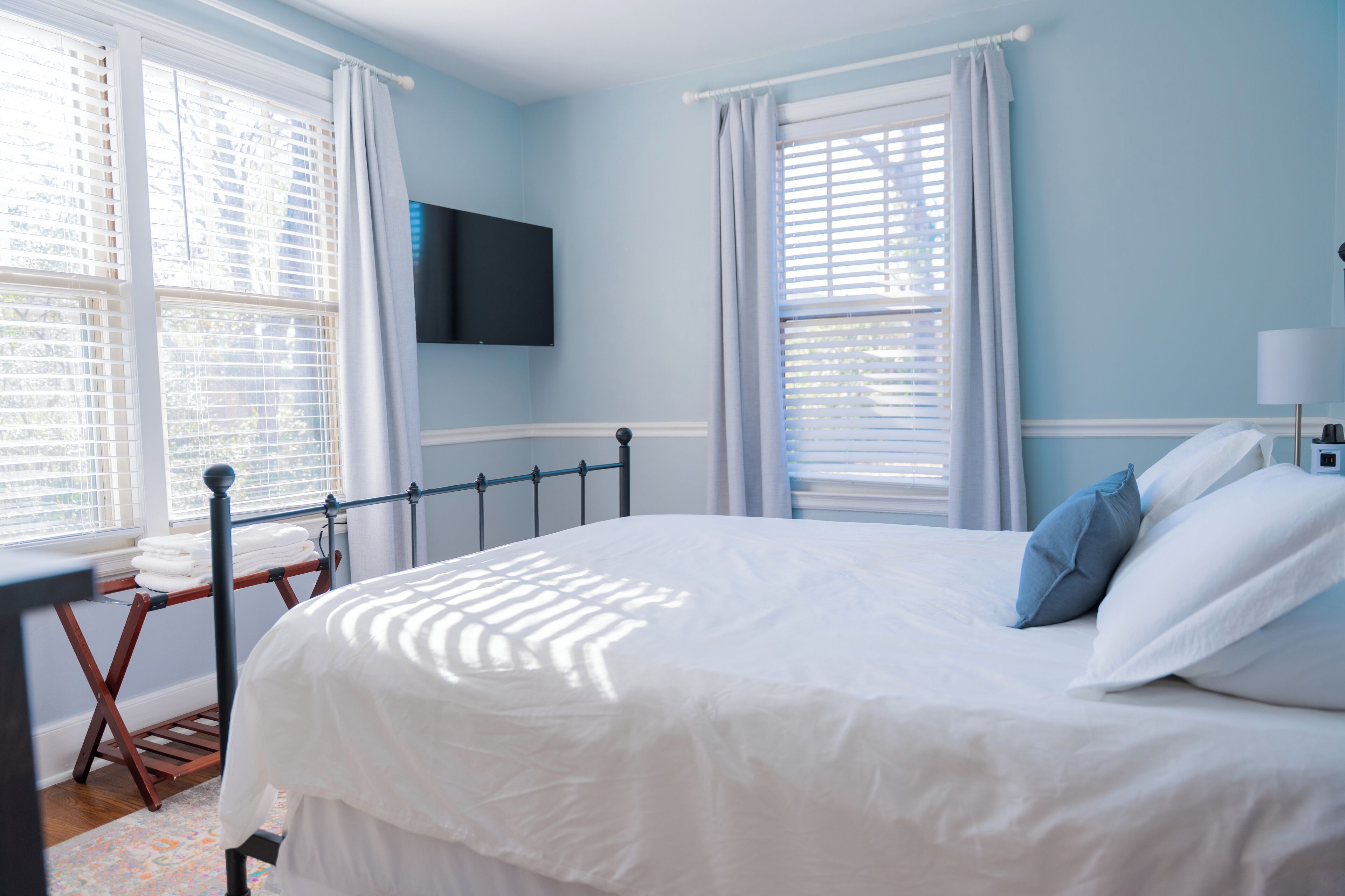 Une chambre à coucher avec un lit, un téléviseur fixé au mur et une fenêtre avec des stores.
