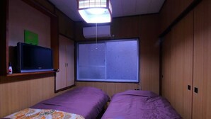 A room with two beds, a television on a shelf, and a window with a view. - Kyomachiya near the World Heritage Toji (Toyodacho)