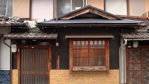 A traditional Japanese house with a tiled roof, wooden doors, and a small window with a wooden frame. - Kyomachiya near the World Heritage Toji (Toyodacho)