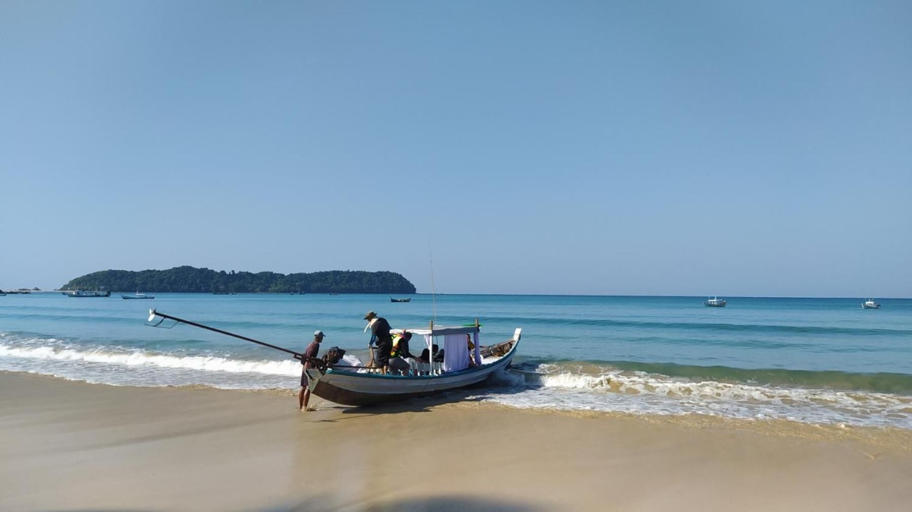 Un bateau sur une plage, avec une eau calme et une île au loin.