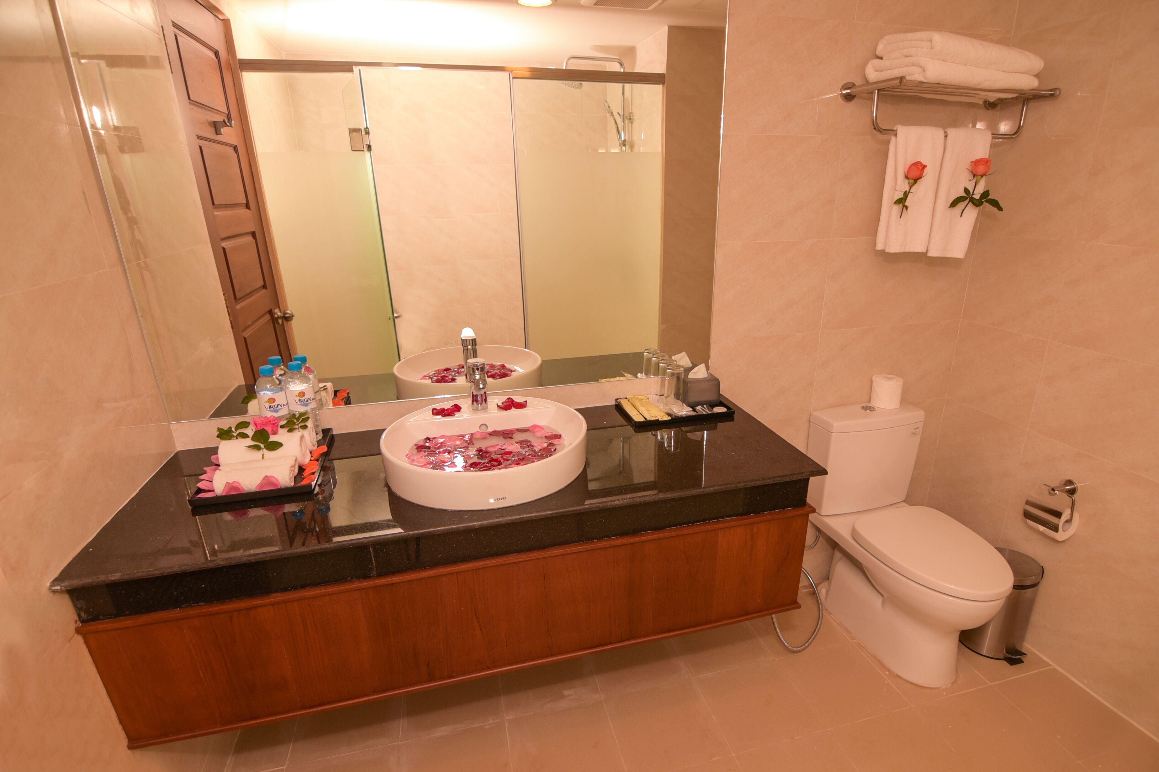 A bathroom with a double sink, a toilet, and a large mirror.