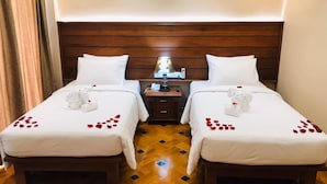 Une chambre d’hôtel avec deux lits, des têtes de lit en bois, une table de chevet avec une lampe et un plancher en bois.