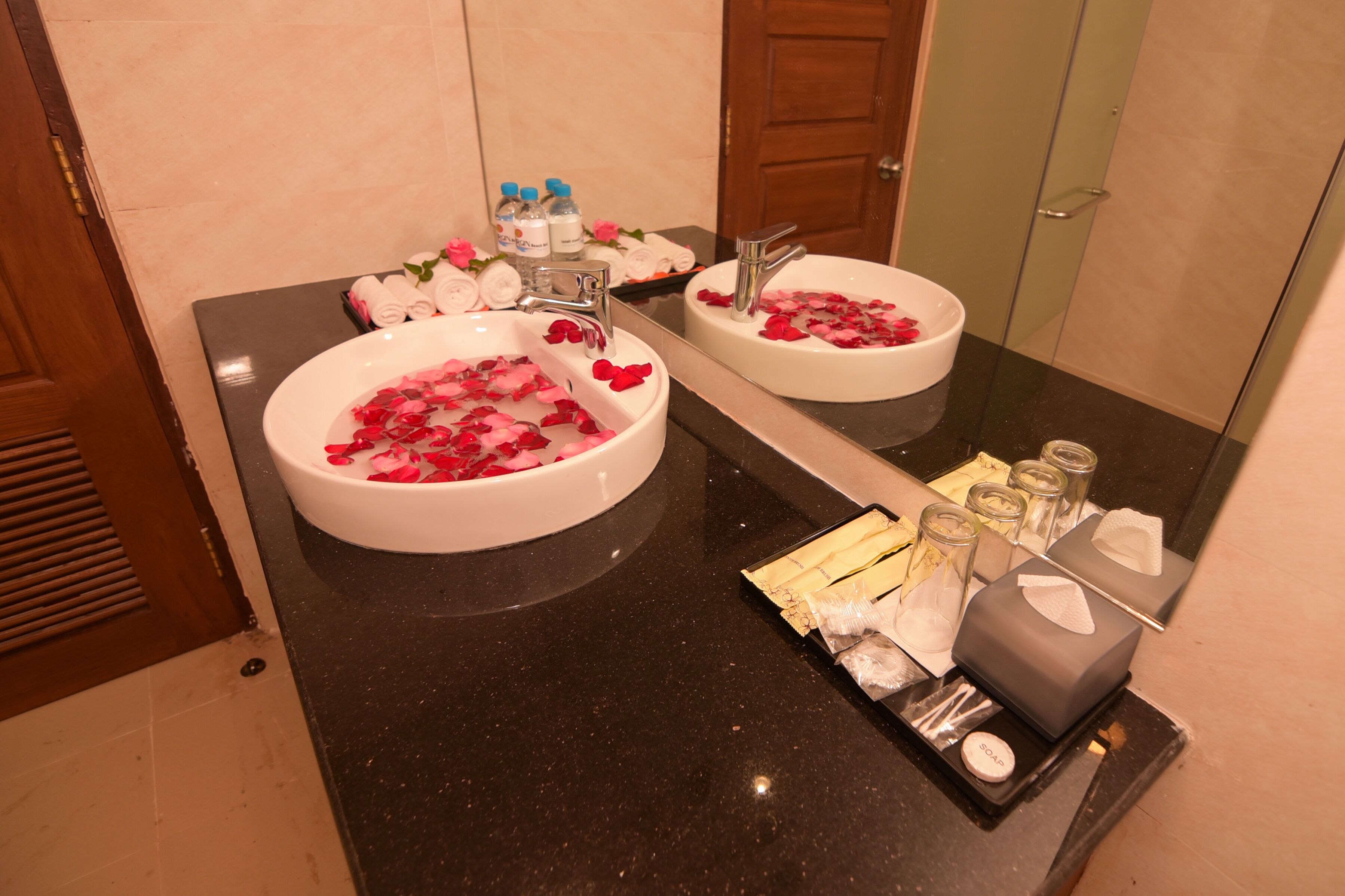 A bathroom with two sinks, a mirror, and toiletries on the counter.