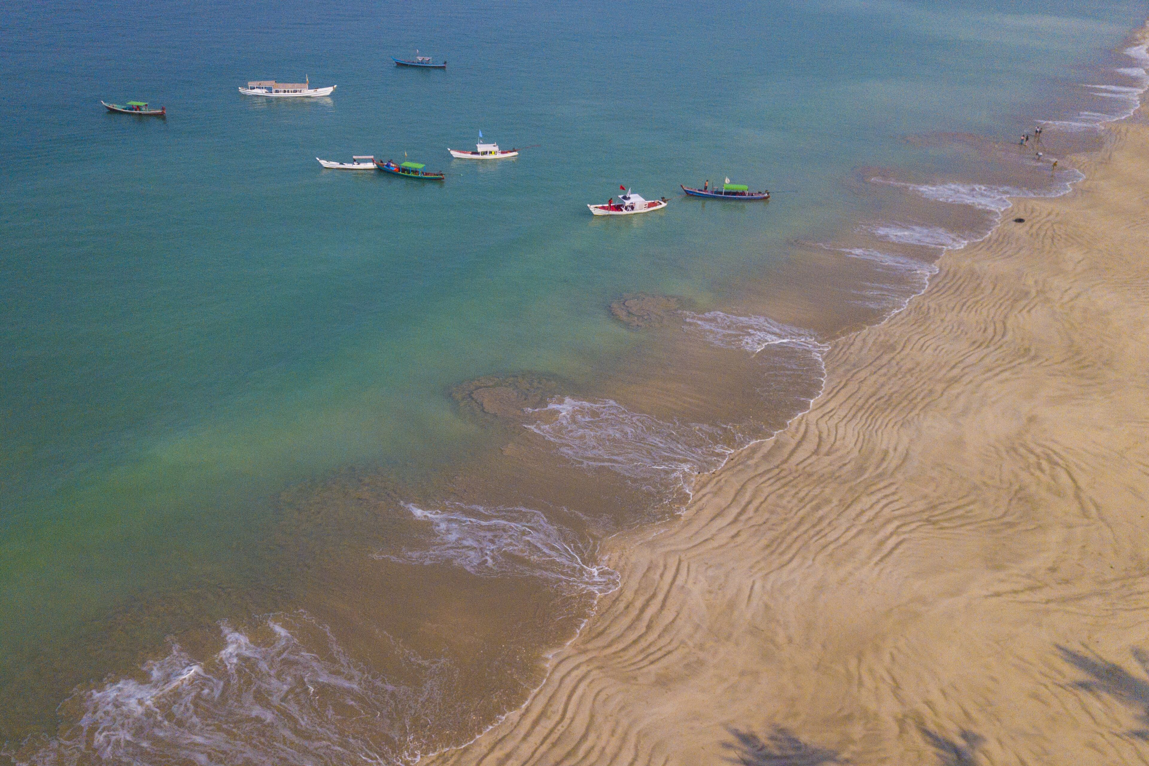A beach with boats and calm water.
