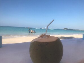 Un coco con una pajita en la playa.