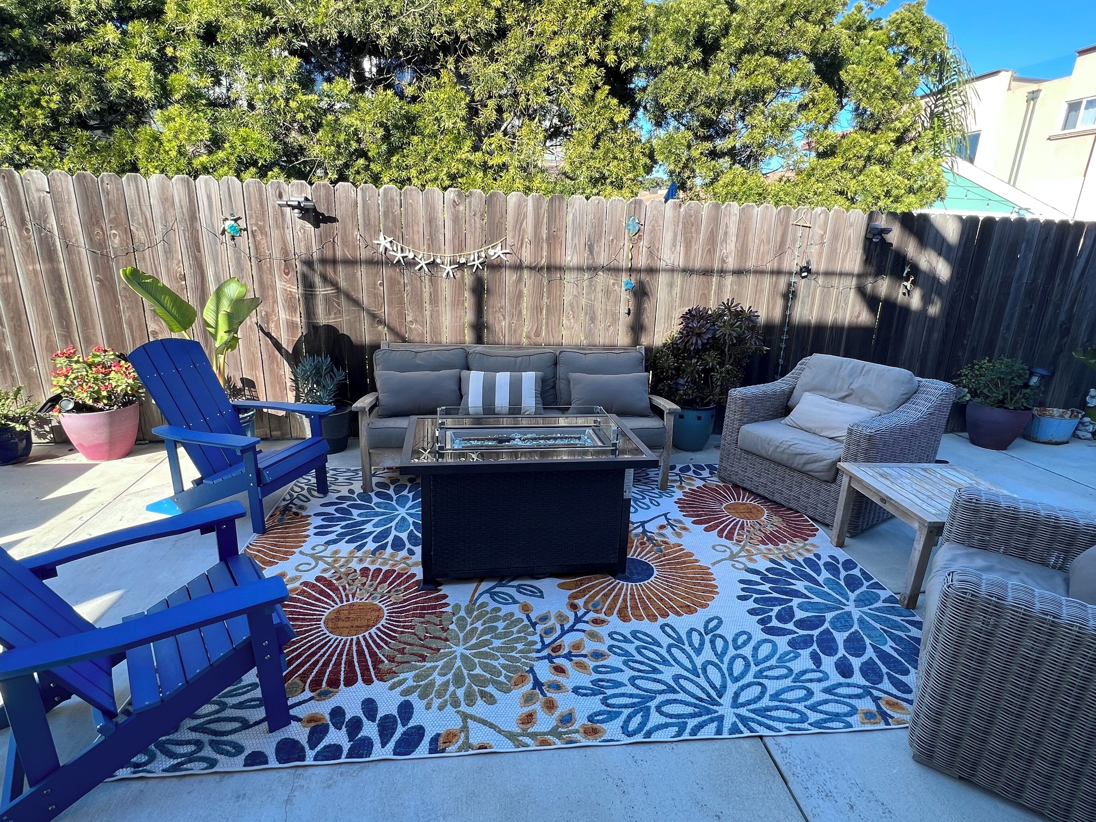 Spacious fenced in patio with seating, dining table, bbq and fire pit.