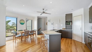 Una cocina moderna con una isla central, suelo de madera y un comedor con sillas y una mesa.