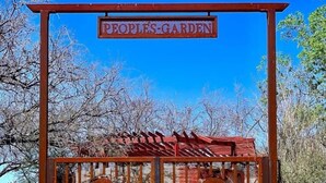A metal gate with a sign reading "Poplars Garden" above it, leading to a wooden structure with a red roof.