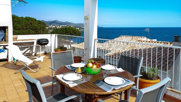 Une terrasse avec une table dressée pour deux personnes, donnant sur la mer.