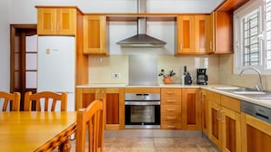 A kitchen with wooden cabinets, a Bosch refrigerator, an oven, and a sink. - Beautiful Villa “Sa Vinyeta” with Mountain View, Air Conditioning, Pool & Terrace (Sant Joan de Labritja)