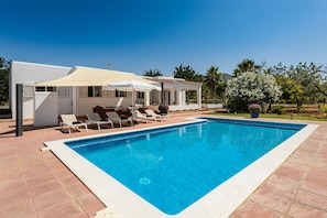 Ein Swimmingpool mit Liegestühlen und Sonnenschirmen, umgeben von einer Terrassenanlage.