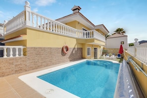 Piscina com balaustrada branca, boia salva-vidas e um guarda-sol vermelho.
