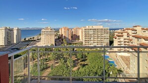 A high-rise building with multiple balconies overlooking a coastal area, featuring a clear view of the sea and a well-maintained garden area. - One bedroom apartment in Veneziola (La Manga del Mar Menor)