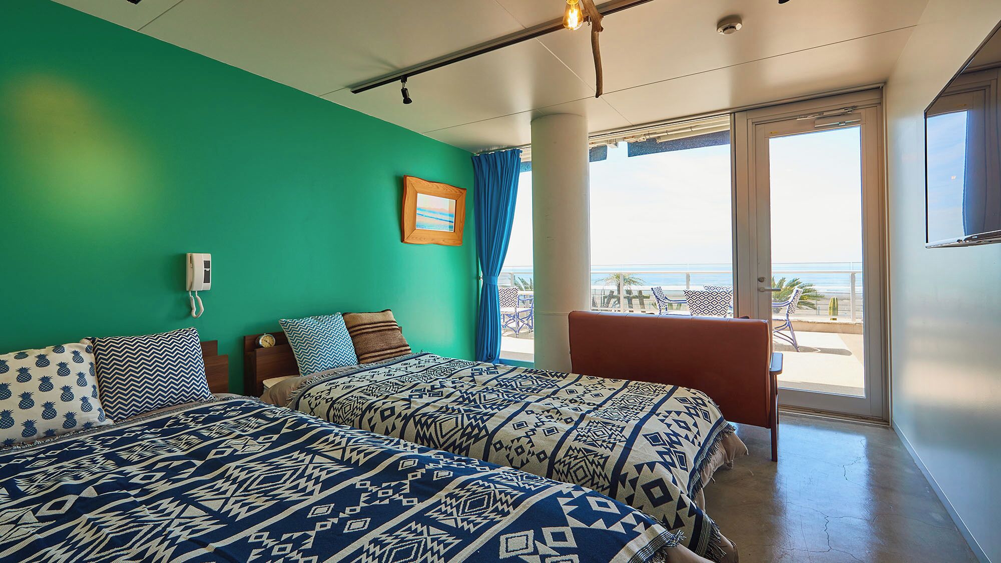 Ein Zimmer mit zwei Betten, einem Sessel, einem großen Fenster und Meerblick.