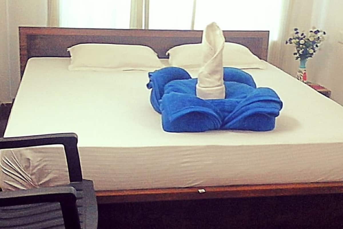 Una cama bien hecha con una almohada blanca y una toalla doblada sobre la cama.