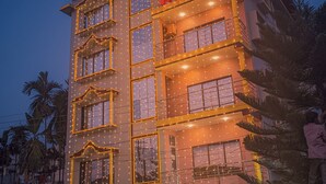 A multi-story hotel with balconies and string lights. - Hotel Greenwood (Siliguri)