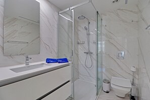 Ein modernes Badezimmer mit einer Duschkabine aus Glas, einem weißen Waschbecken und einer Toilette.