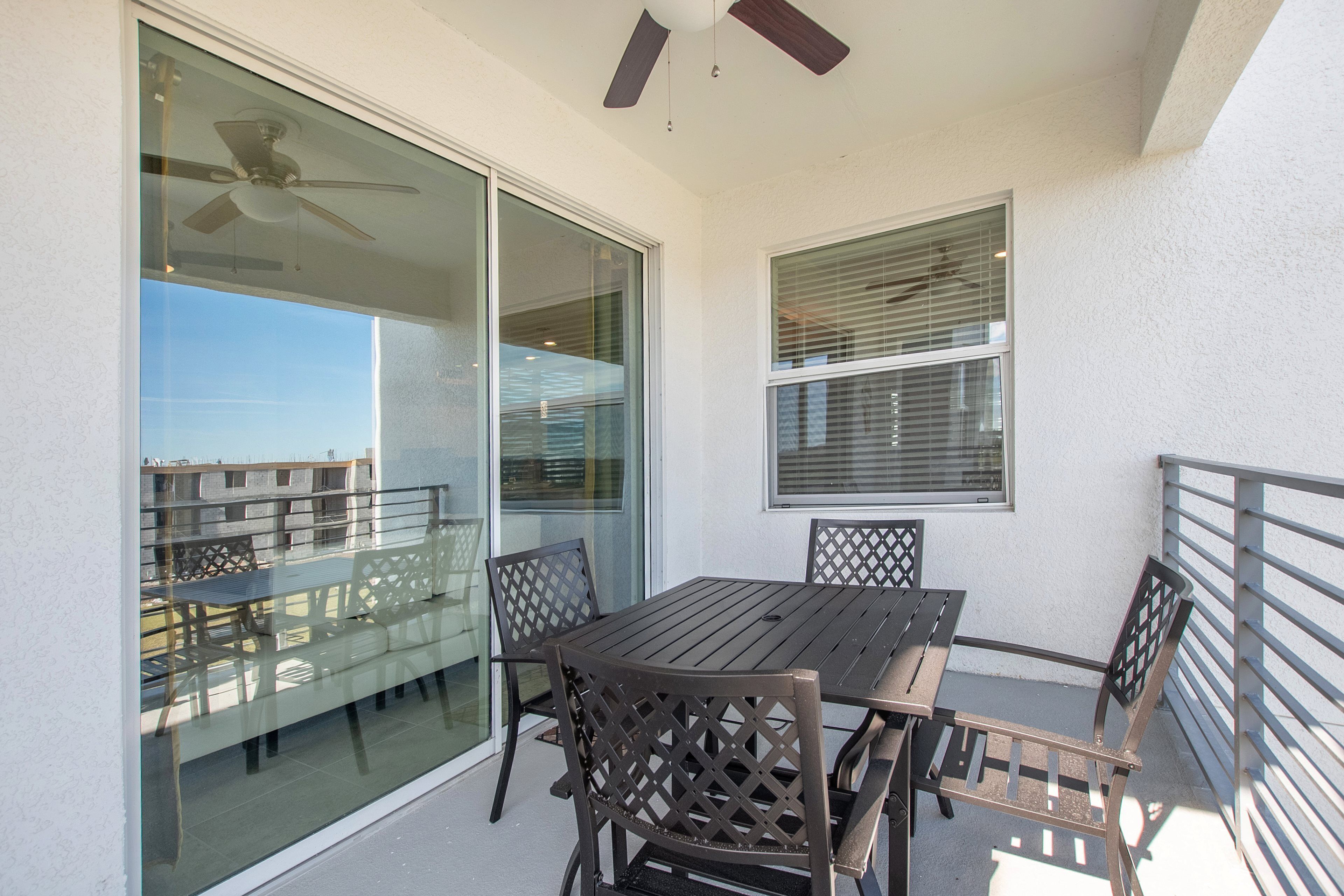 A balcony with a table and chairs, a ceiling fan, and a view of buildings.