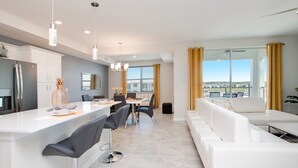 Eine moderne Küche mit Kochinsel, Essbereich mit weißer Möbel und ein großes Fenster mit Blick.