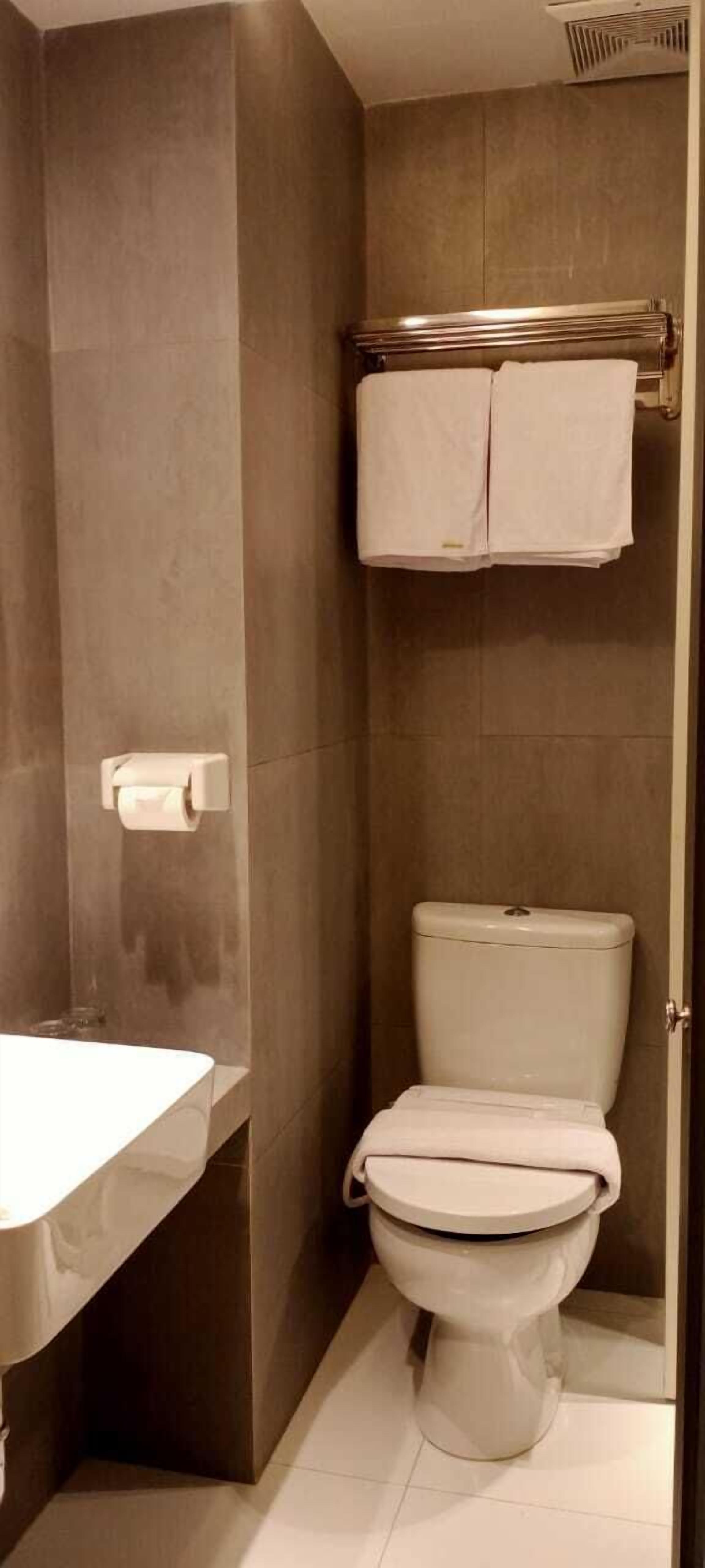 Uma casa de banho moderna com sanita, lavatório e suporte para toalhas.