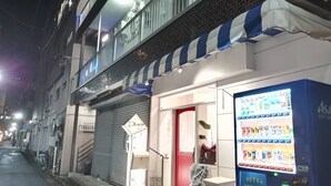 A hotel with a red door and a vending machine on the sidewalk. - A0 Kinshichou 201 (Tokyo)