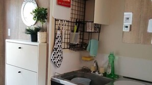 A compact kitchen with a sink, a small countertop, and a cabinet with a mirror. There is a sign above the sink and a plant on the counter. - A0 Kinshichou 201 (Tokyo)