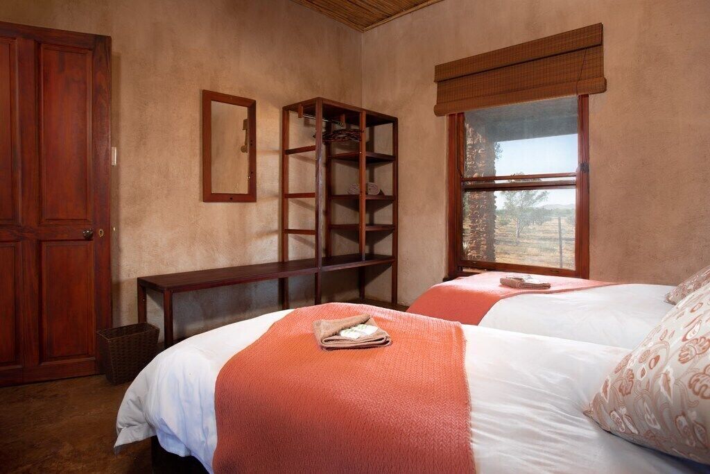 Un dormitorio con dos camas, un armario de madera, una estantería y un ventanal con vistas.